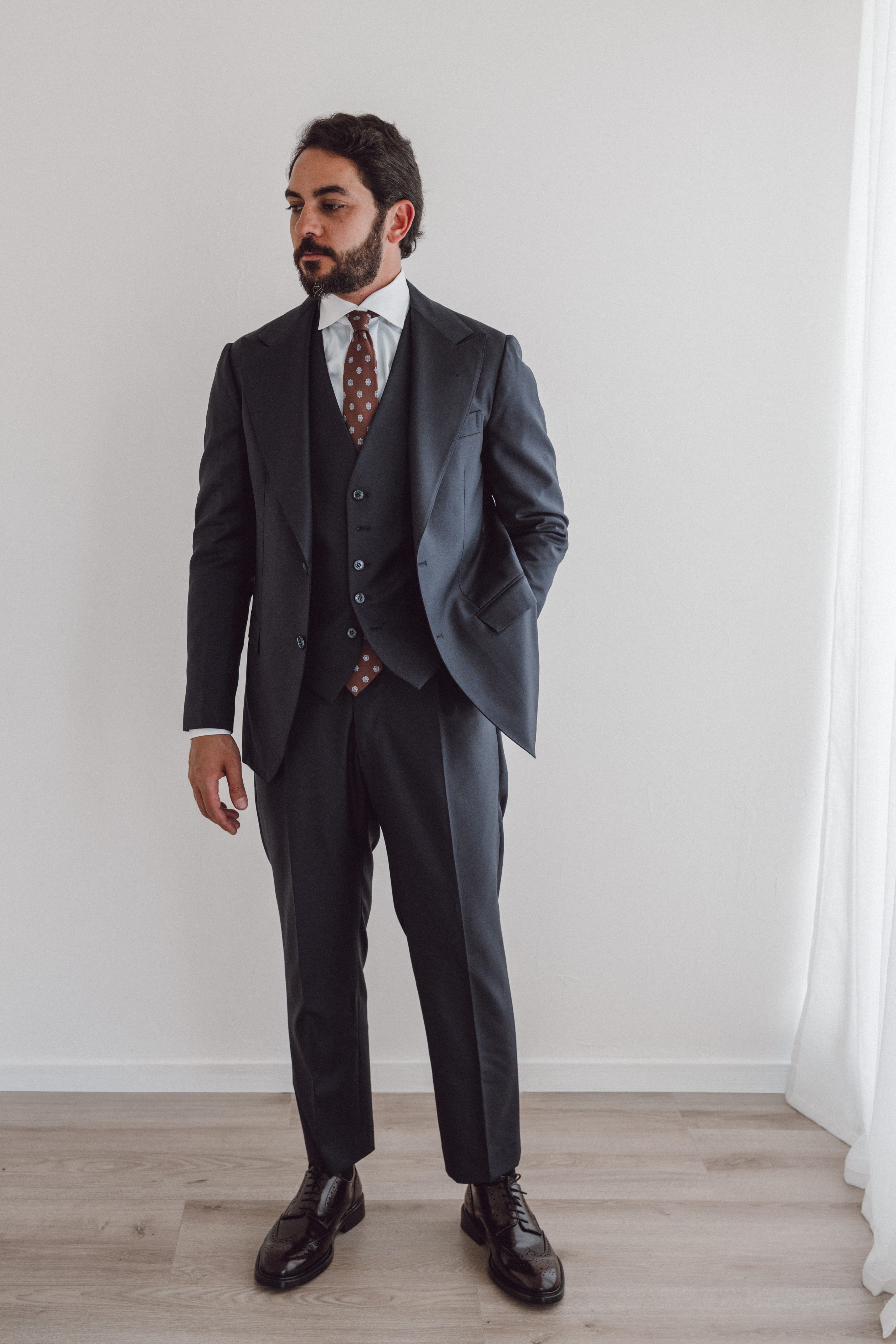 FK Bespoke client in a charcoal three-piece suit checking his cuff